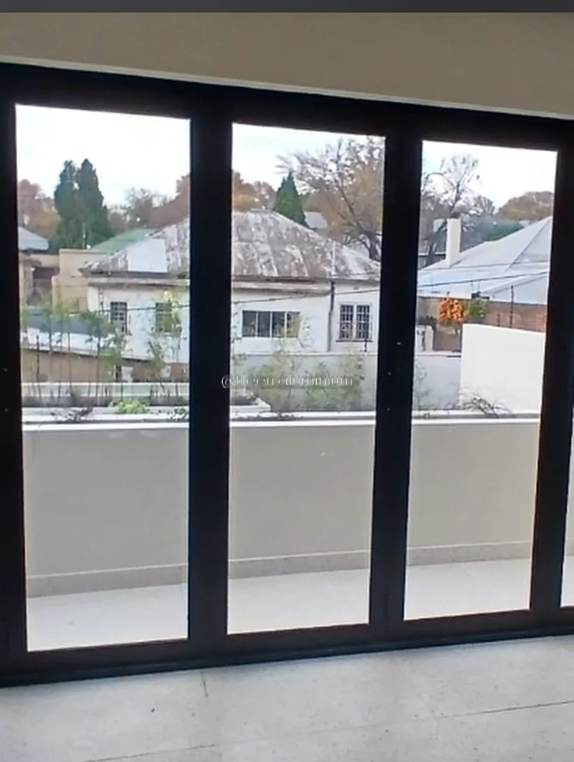 Charcoal aluminium stacking doors opening onto a balcony above a rooftop view