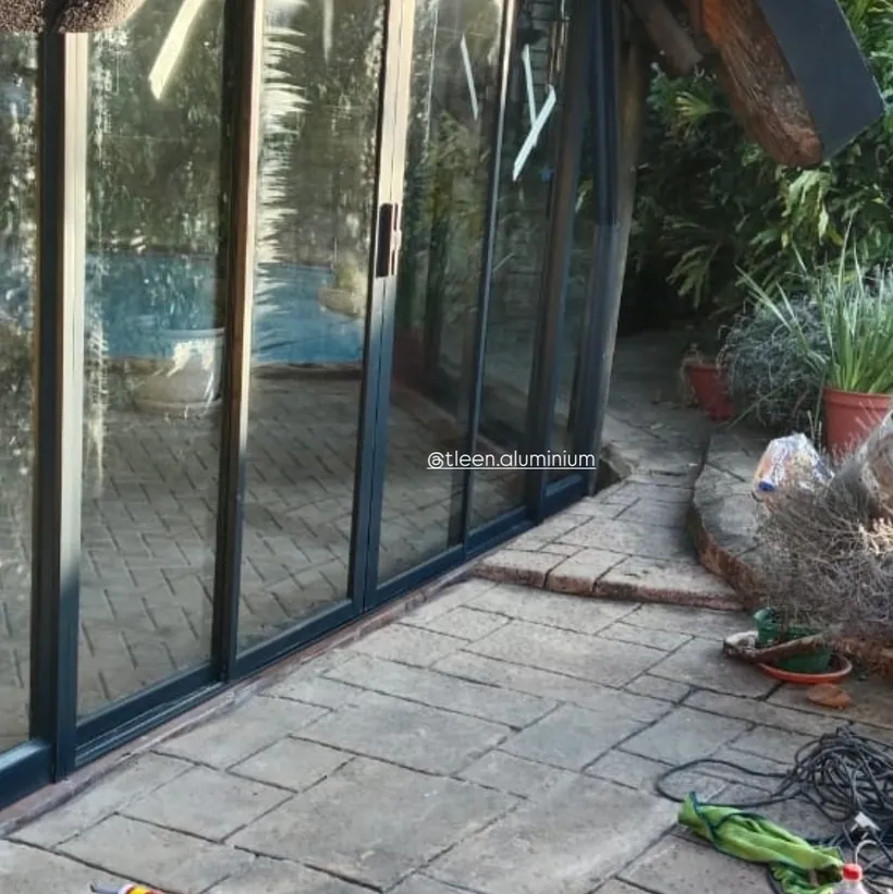 Four-panel charcoal aluminium sliding door onto a paved garden patio