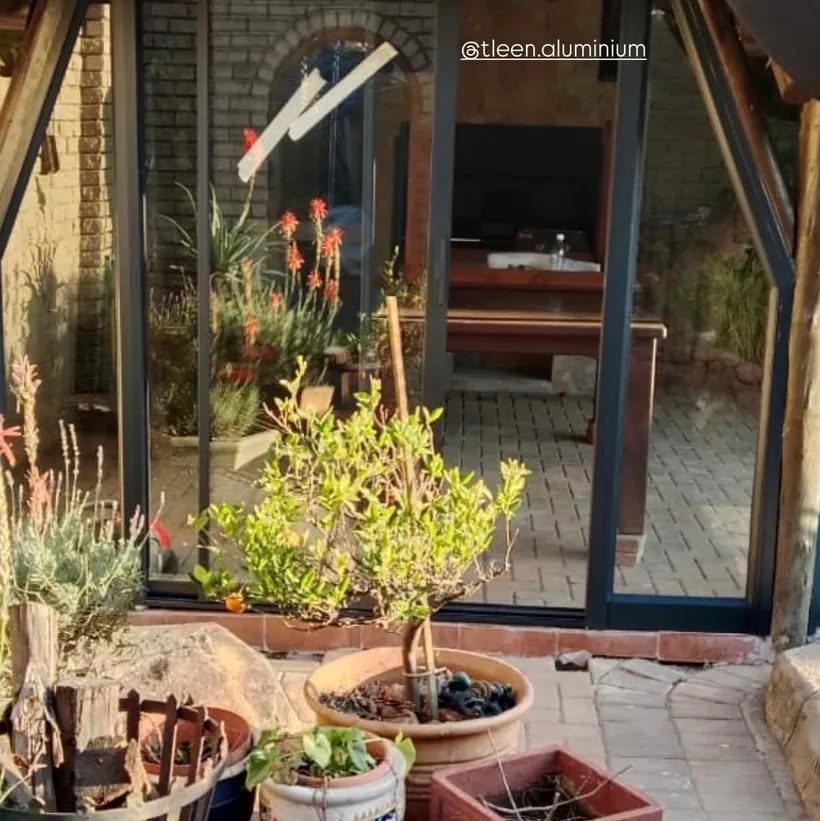 Corner glazing in charcoal aluminium framing a planted courtyard