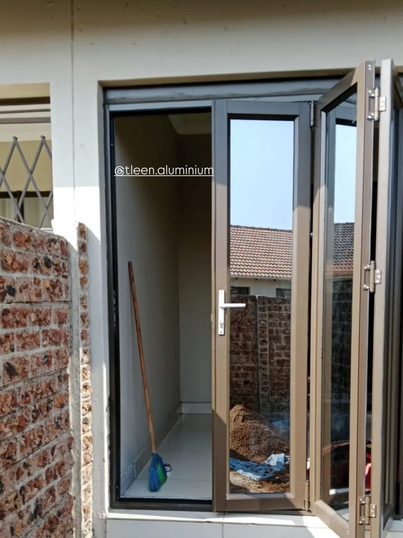 Charcoal aluminium folding door fitted into a face-brick opening