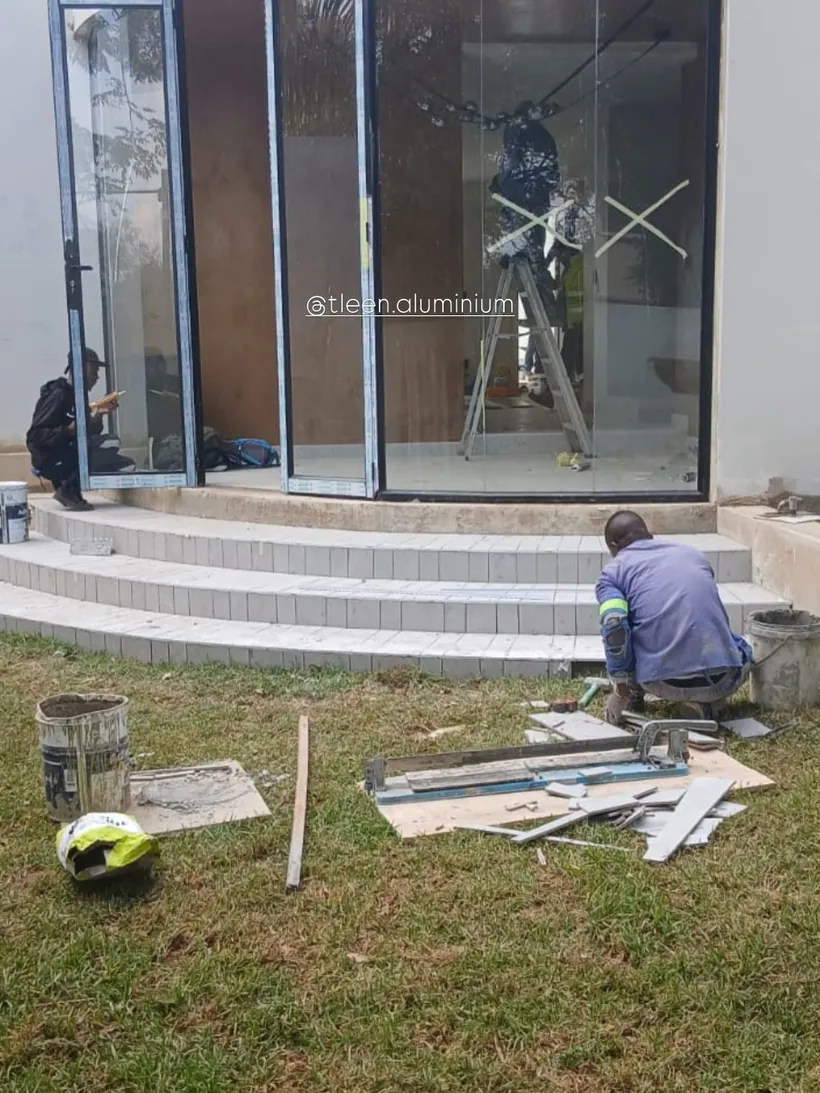 Installer fitting a large stacking door unit onto a garden elevation