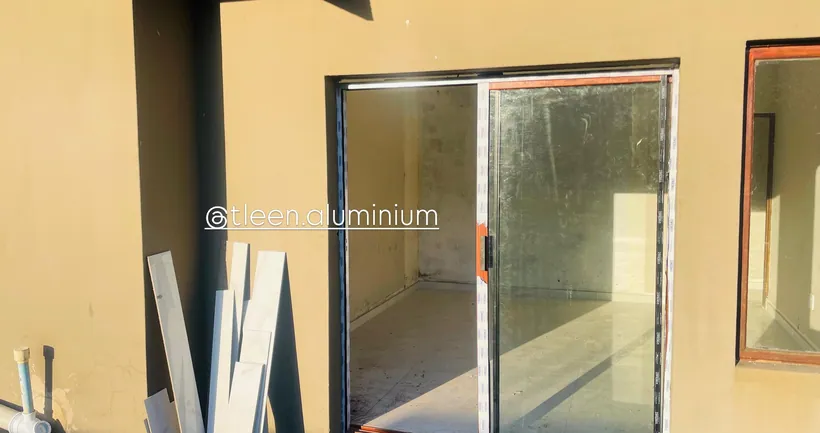 Wood-look aluminium sliding door in a yellow-plastered wall