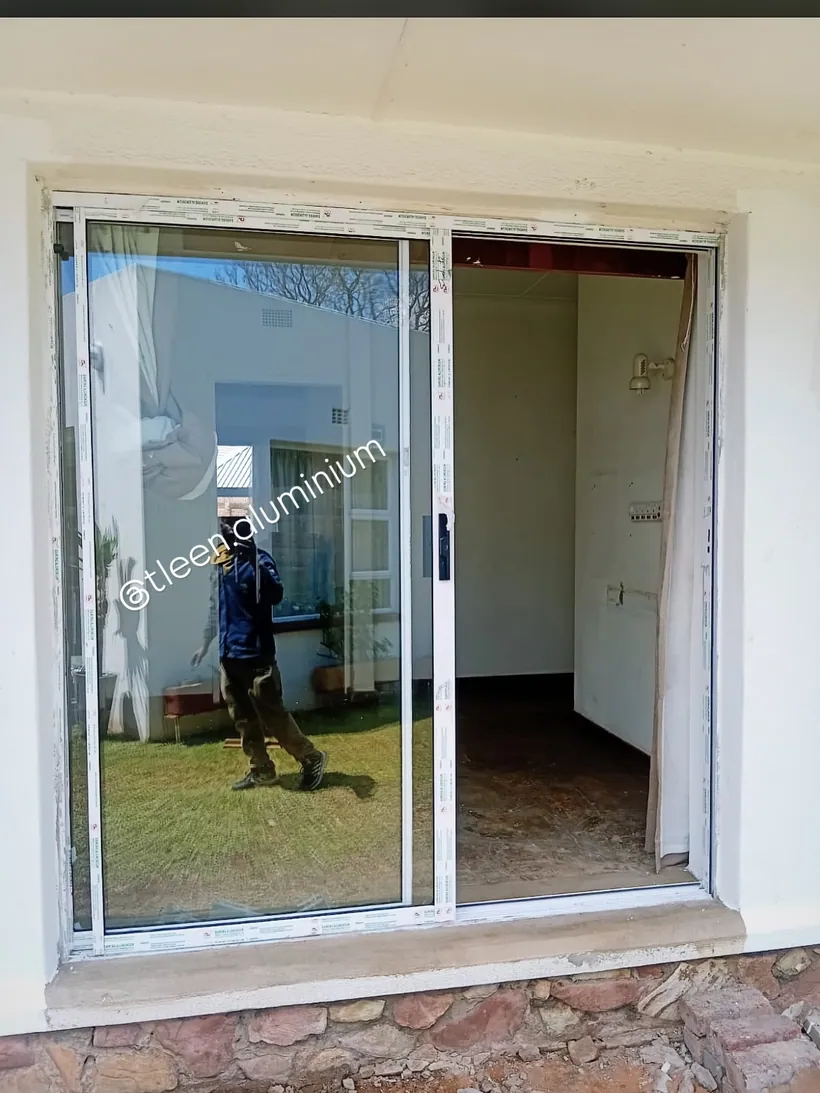 White aluminium sliding door being installed in a face-brick opening