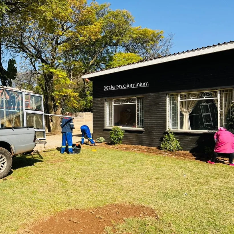 Installation team working across the front elevation of a dark-painted house
