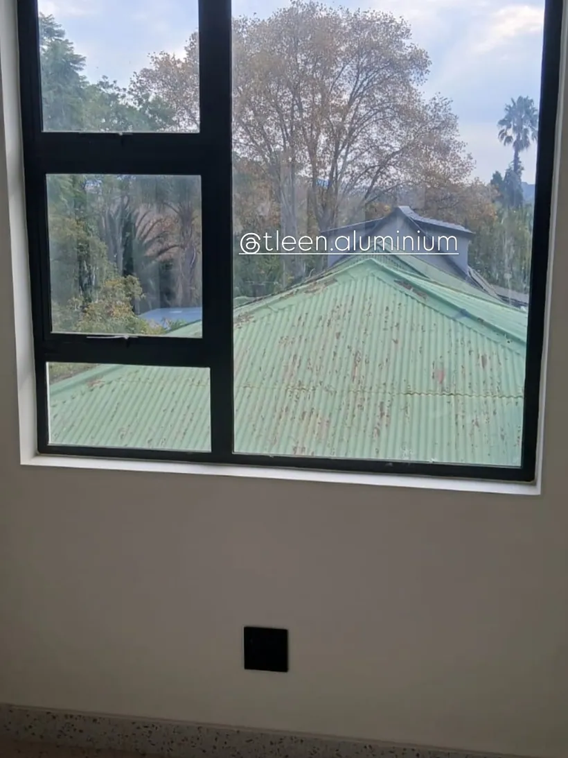 Charcoal aluminium fixed and top-hung window looking into tree canopy