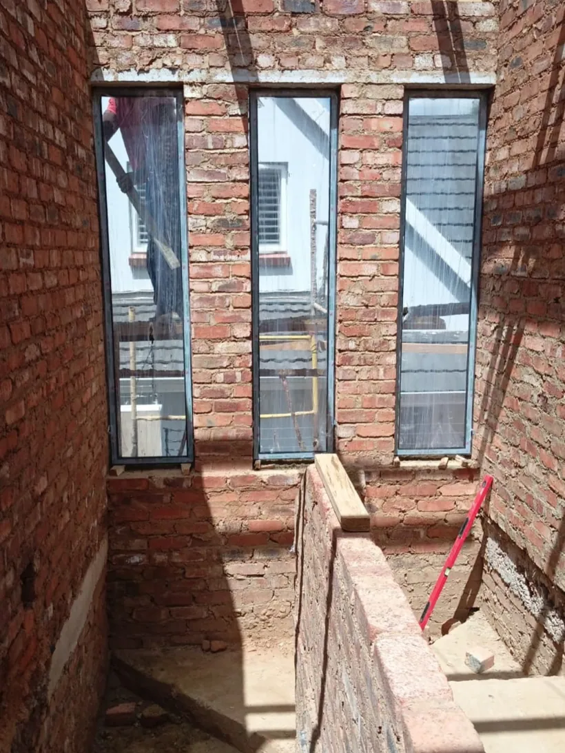 Tall narrow charcoal aluminium window panels in a new-build brick shell
