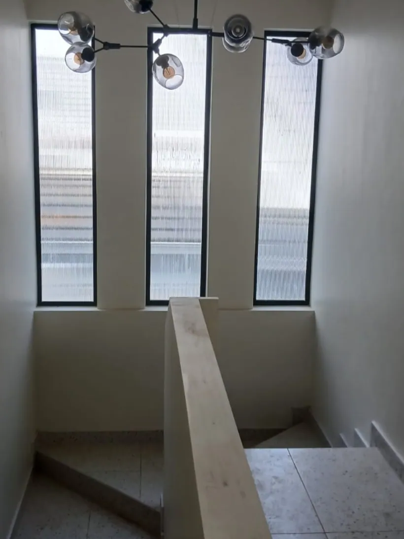 Full-height charcoal window panels lighting an internal stairwell