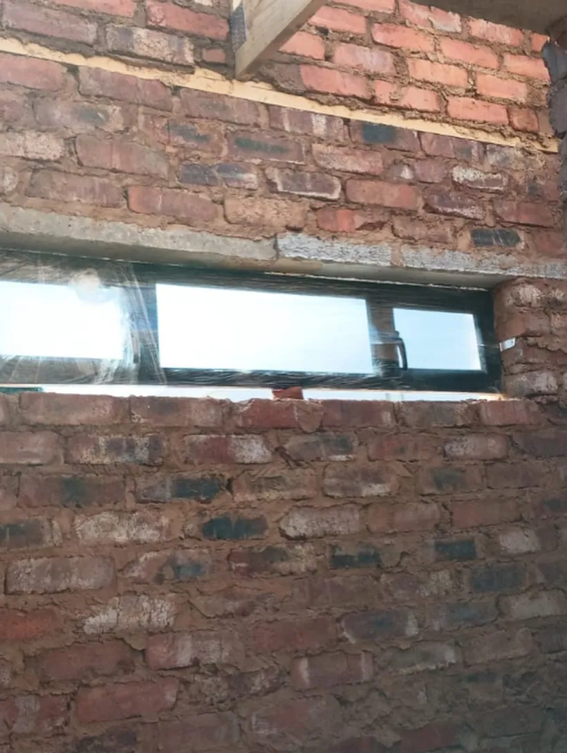 Long horizontal charcoal awning window set into a face-brick wall