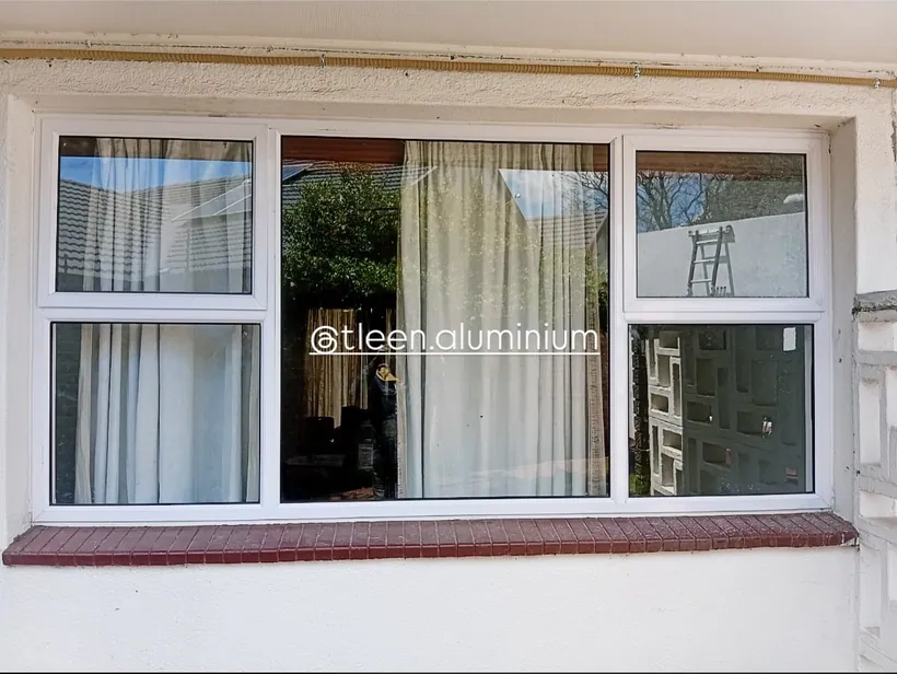 White aluminium top-hung window with curtains drawn back
