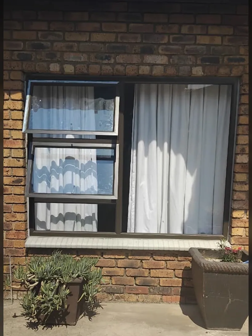 Charcoal top-hung window with a burglar guard on a brick house